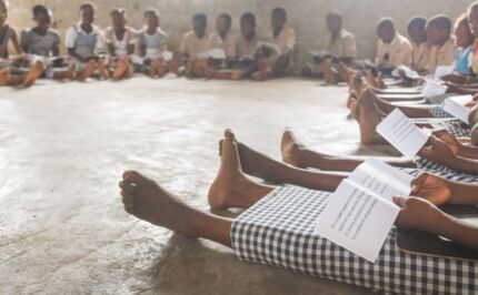 Close up on bare feet as pupils sit on the floor of their classroom